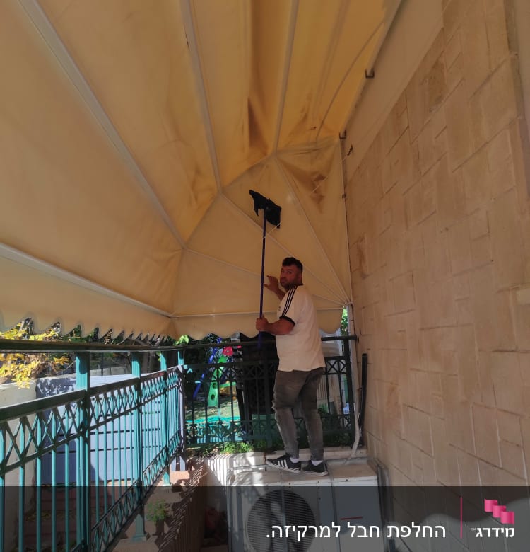 אדם מנקה סוכך בעזרת מטאטא ארוך